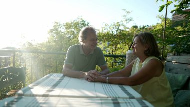 Mutlu olgun çiftler el ele tutuşup yaz boyunca romantik bir öğleden sonra güneşinde birbirlerine bakıyorlar. Neşeli yaşlı adam ve kadın