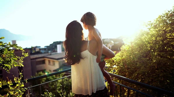 先頭へ戻る母と子供の日没時に風光明媚な風景を見下ろす 黄金の時間の間に腕の中で息子を保持ママ — ストック写真