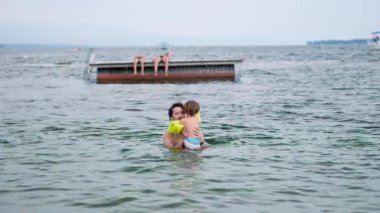 Babası göl suyunda oğluyla bağ kuruyor. Şişirilebilir kolluk takan bir çocuk. Babalık yaşam tarzı kavramı birlikte yüzüyor.