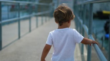 Düşüncelere dalmış, Bay Bridge 'de yürüyen dalgın bir çocuğun sırtında. Düşünceli küçük çocuk dışarıda demiryoluna tutunurken hayatı düşünüyor.