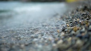 Deniz kıyısını kapatın. Sakin okyanus suyu dalgaları kayalık sahile vuruyor. Soyut doğa arka plan seyahati rahatla. 240 fps ağır çekim