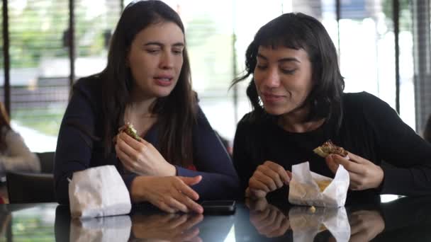 Teman Perempuan Berbagi Layar Telepon Sambil Makan Burger Duduk Restoran — Stok Video