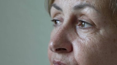 Düşünceli, olgun bir kadın meditasyonda ufka bakarak gözlerini kapatır. 70 'li yaşlarda yaşlı, dalgın bir kadın. Düşünceli ifade