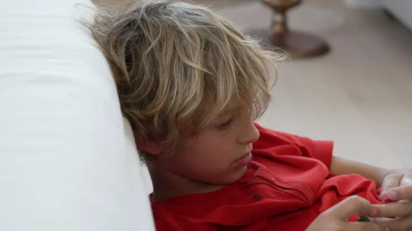 stock image One bored little boy leaning on sofa at home. Close up child with feeling boredom with nothing to do