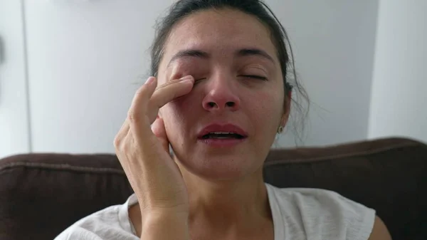 Sad woman taking a deep breath feeling anxious. Crying female person close up face with desperate expression and rubbing eye with hand during hard times