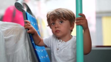 Küçük çocuk toplu taşıma otobüsünde sandalyede oturuyor. 