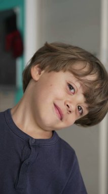 Şakacı, küçük bir çocuk kameraya bakıyor. Dikey Videodaki sevimli bir çocuğun portresi