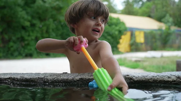 一个小男孩夏天在外面玩水玩具枪 从公共喷泉取水的儿童 — 图库照片