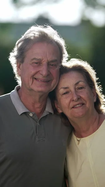 年上の夫婦の笑顔を閉じます 太陽の下で屋外に立つカメラのポーズのシニアカップルの肖像画 — ストック写真