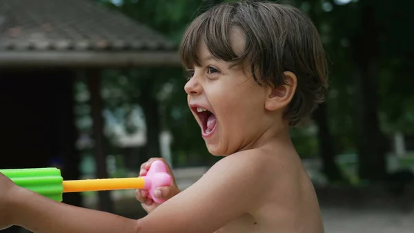 一个快乐的小男孩在户外喷水玩乐 兴奋的小孩在外面玩泡沫水爆竹 游泳池玩具 — 图库照片