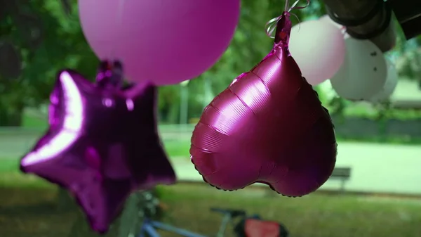 Close up of birthday balloons decoration outside. Purple color with green nature background