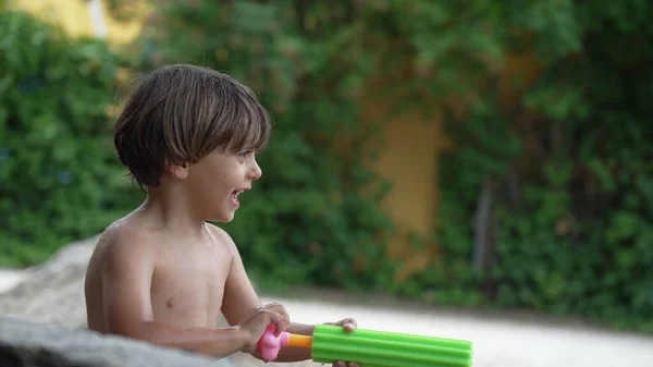 어린이는 여름날 뒷마당에서 장난감 주머니를 사용하여 뿌리고 노는아이 — 스톡 사진