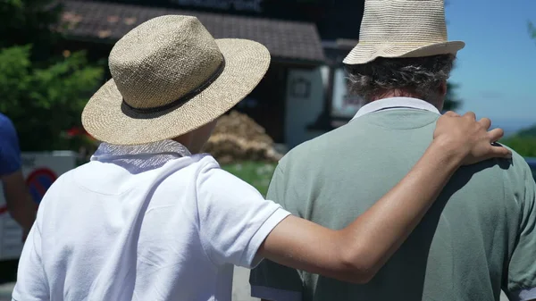 Back Son Embracing Father Arm Walking Together Wearing Panama Hats — Stockfoto