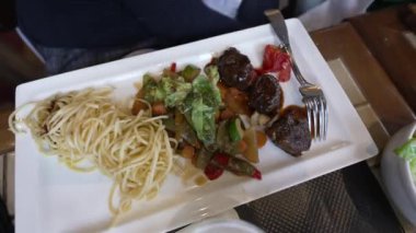 Restoran yemeği tabakta kapanış yemeği. Etli makarna ve sebzeli salata. Öğle yemeğinde yakın yemek.