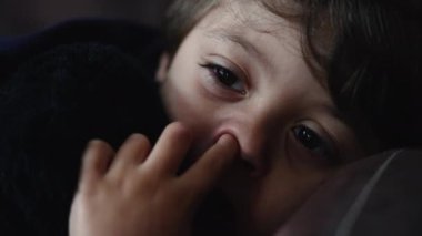 Dalgın küçük çocuk burnunu karıştırıyor. Yakından erkek, düşünceli çocuk burnunu karıştırıyor.