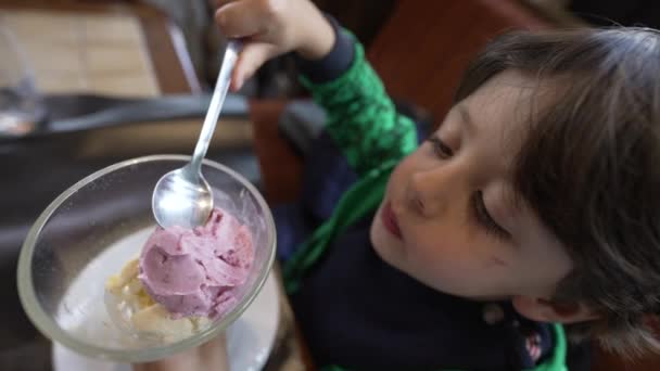 Küçük Bir Çocuk Restoran Masasında Oturmuş Kasede Çilekli Dondurma Yiyor — Stok video
