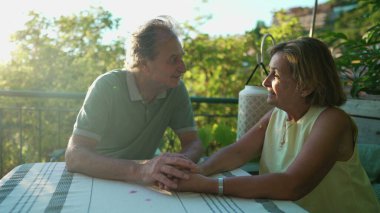 Mutlu olgun çiftler el ele tutuşup yaz boyunca romantik bir öğleden sonra güneşinde birbirlerine bakıyorlar. Neşeli yaşlı adam ve kadın