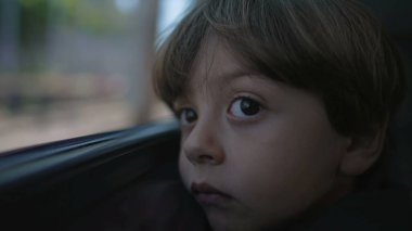 One sad little boy leaning on train window. Close up face of contemplative child. Thoughtful kid with serious expression