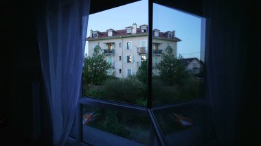 Gün batımının alacakaranlık saatinde pencere camları yansıyor. Akşamları Avrupa binasının mavi huysuz tonu