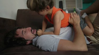Baba, evdeki kanepede birlikte oynayan küçük çocukla bağ kuruyor.