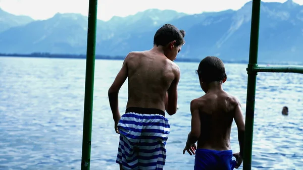 两个小男孩站在码头后面 小孩跳入湖水里 湿孩子享受暑假 儿童跳楼 — 图库照片
