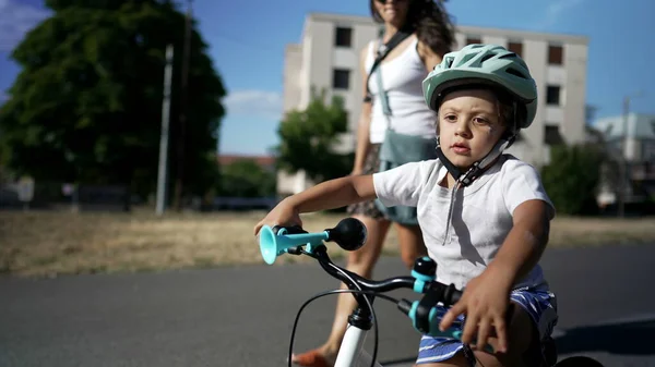 Child riding bike outdoors wearing protective helmet. Active little boy exercising learns to ride bike in balance