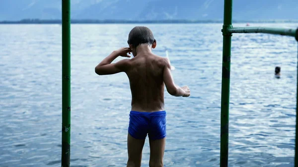 의물이 내려다 보이는 부두에서 소년의 자녀가 여름휴가를 즐기게 — 스톡 사진