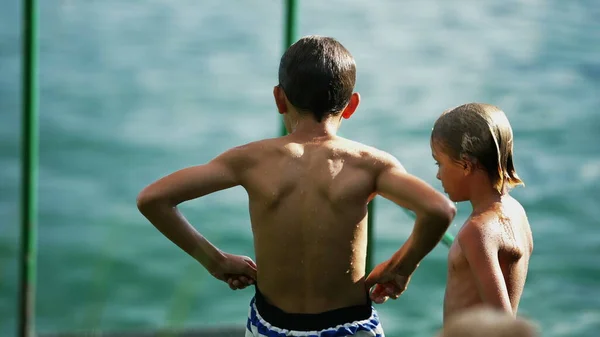 Göl Kenarında Duran Iki Islak Çocuğun Arkasında Mayo Ayarlayan Genç — Stok fotoğraf