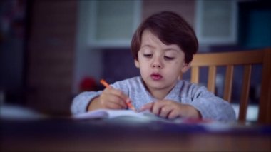 Küçük çocuk renkli kalemle çiziyor. Çocuk masada bir resim çiziyor. Evde çocuk boyama