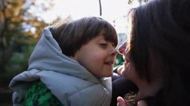 Mutlu anne ve çocuk Eskimo öpücüğü yapıyor. Burunları dışarıda, güneş ışığıyla parlıyor. Annelik yaşam tarzı konsepti