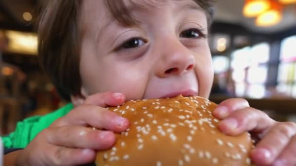 Kind Neemt Een Hap Hamburger Close Gezicht Kleine Jongen Met — Stockvideo