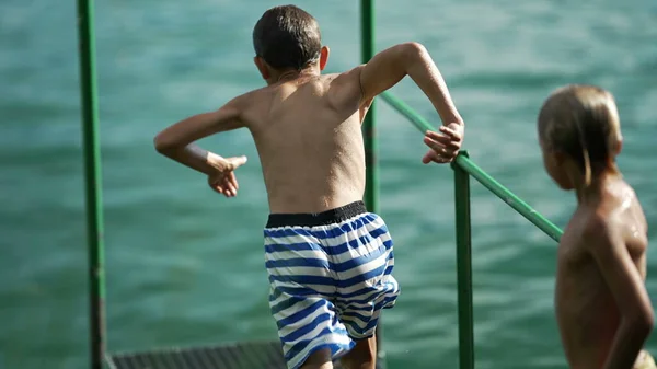 속으로 아이들은 부두에서 동작으로 호수에 듭니다 아이들 여름휴가 재미있게 — 스톡 사진