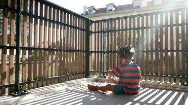 Mutlu Çocuk sabah apartmanın balkonunda oturuyor. Terasta küçük bir çocuk. Evde sabahları pijama giyip lens takıyor.