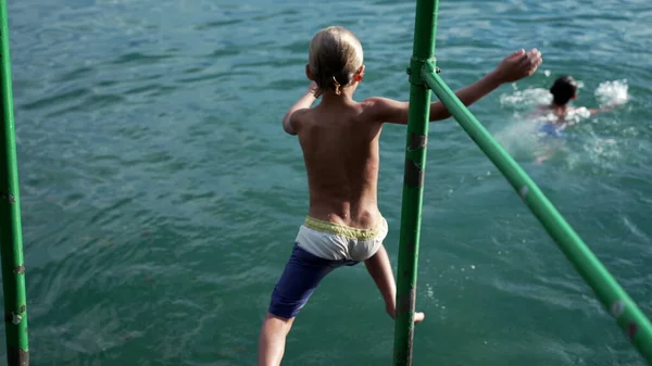 一个小男孩跳进了水里 小孩跳进湖里孩子们在户外享受夏天的快乐 — 图库照片