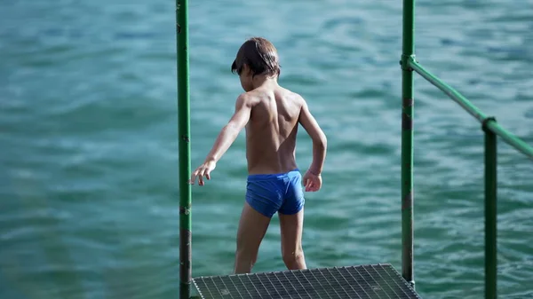 水着を着た湖のデッキのそばに立っている男の子 休暇中に屋外で自然の中で夏休みを楽しむ子供 — ストック写真