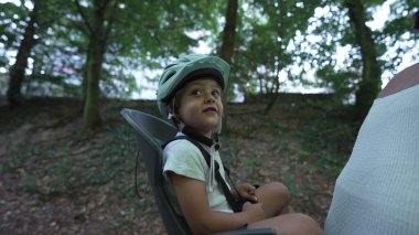 Arka koltukta koruyucu kask takan mutlu bir çocuk. Çocuk ailesiyle bisiklete biniyor. Güvenli ve koruma kavramı