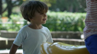 Çocuk atlıkarıncayı itiyor. Çocuk şehir parkında eğleniyor.