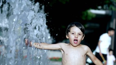 Mutlu çocuk sıcak yaz gününde 120 fps yavaş çekimde su parkı jetlerinde eğleniyor.