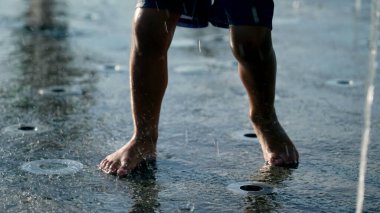 Su sıçratan suyun içindeki çocuk ayakları açık hava parkında oynuyor.