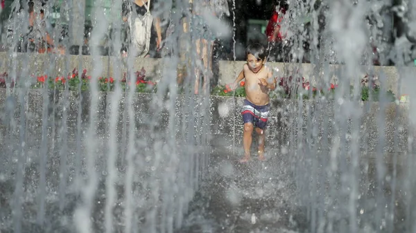여름에는 공원에서 물보라를 다닌다 어린아이는 천천히 흐르는 속에서 뛰놀고 — 스톡 사진