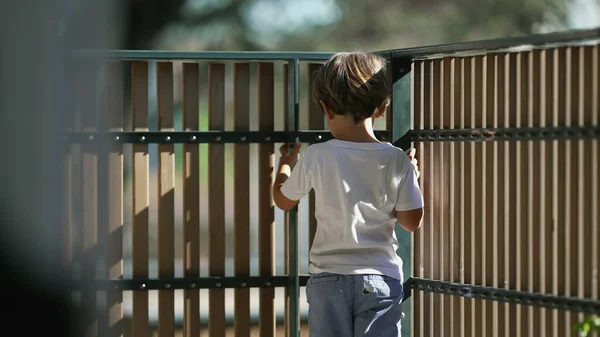 stock image Pensive Little boy holding into balcony wooden fence at apartment building. Concept of security and protection of little boy at residential terrace