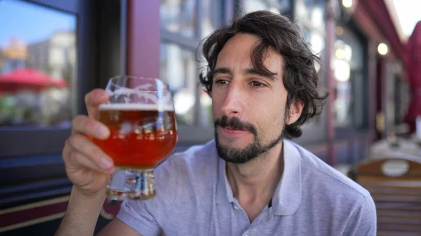 stock image One young man drinking beer outside in city sidewalk. Male person drinks draft pale ale beer at restaurant