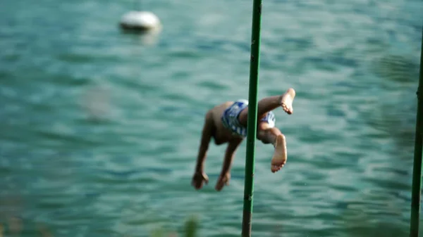 一个小男孩跳入湖水里享受暑假 孩子们在甲板上往清水里泼水 — 图库照片