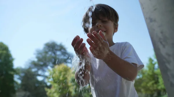 stock image One small boy washing hands in public faucet outside. Child washes hand from fountain slow motion outdoors at city park