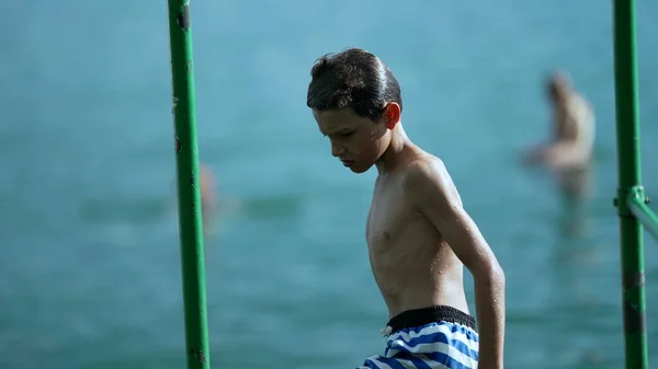 소년은 호수의 옆에서 수영복을 갈아입었다 사려깊은 아이에게 표정을 — 스톡 사진
