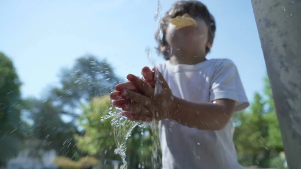 一个小男孩在外面的水龙头里洗手 在公园外 孩子们从喷泉边慢慢地洗手 — 图库照片