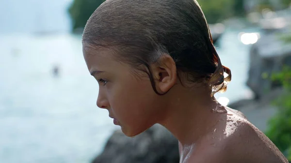 stock image One wet contemplative young boy drying in the sun outside after bathing at lake. Profile of serious pensive child