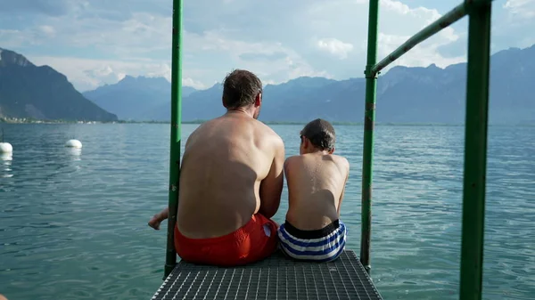 Father Son Sitting Lake Pier Together Overlooking Swiss Mountains Lake — Stockfoto
