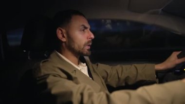Adam endişeli bir şekilde gece araba kullanıyor. Tedirgin Ortadoğulu erkek sürücü otoyolda
