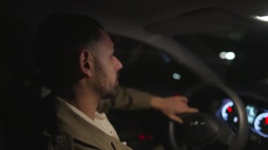 Gecenin bir yarısı direksiyon başında araba süren bir adam. Erkek şoför akşamları araba kullanır.